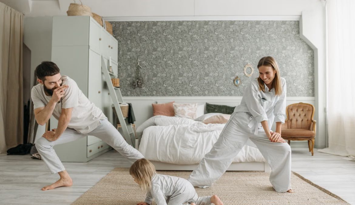 A joyful family bonding through morning stretches in a cozy bedroom setting.