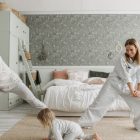 A joyful family bonding through morning stretches in a cozy bedroom setting.