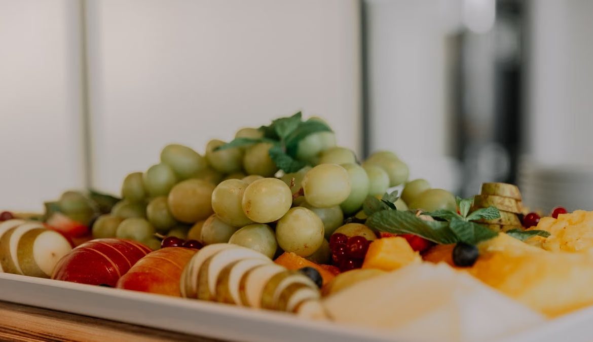 A vibrant assortment of fruits including grapes, apples, and berries on a white tray.